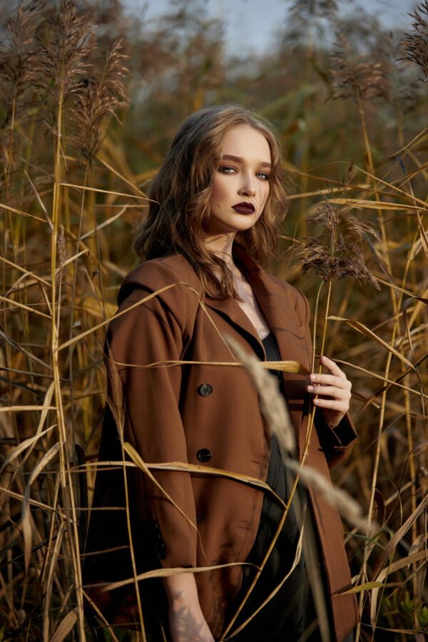 Portrait of a beautiful fashion woman in a thicket of autumn grass