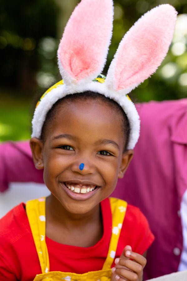 Portrait of smiling cute african american girl wearing bunny ears during easter day